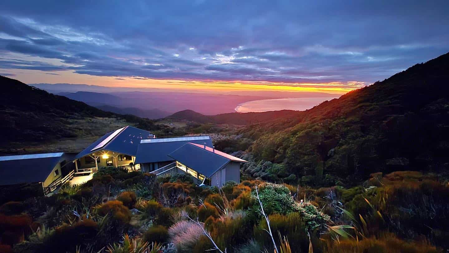 Okaka Lodge nestled in mountainous landscape with sunset view over coastline and ocean