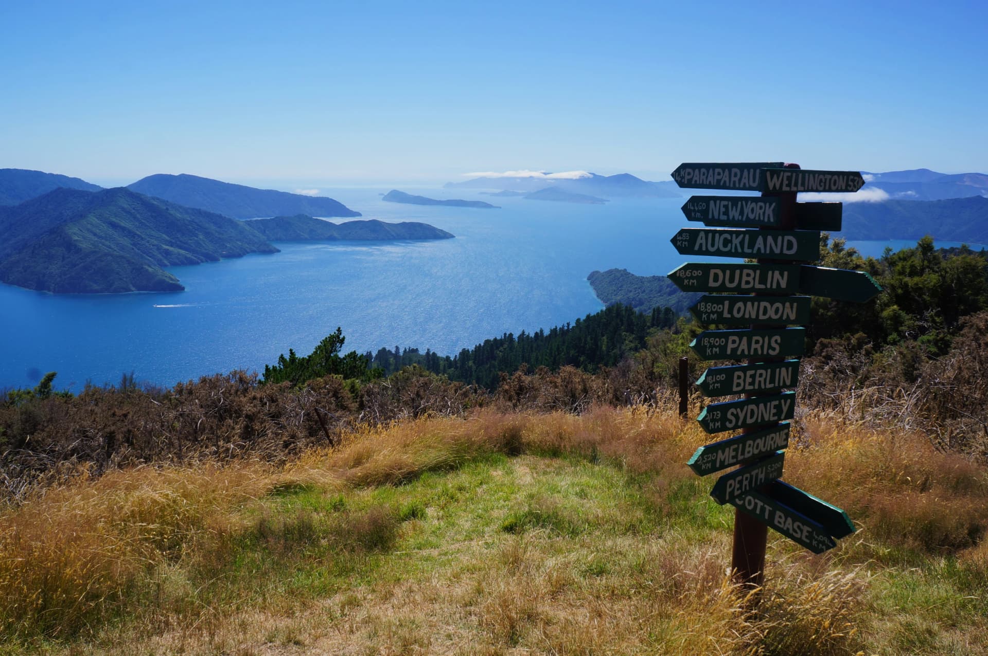 Wooden signpost in Queen Charlotte Track showing distance to international cities around the World, New Zealand