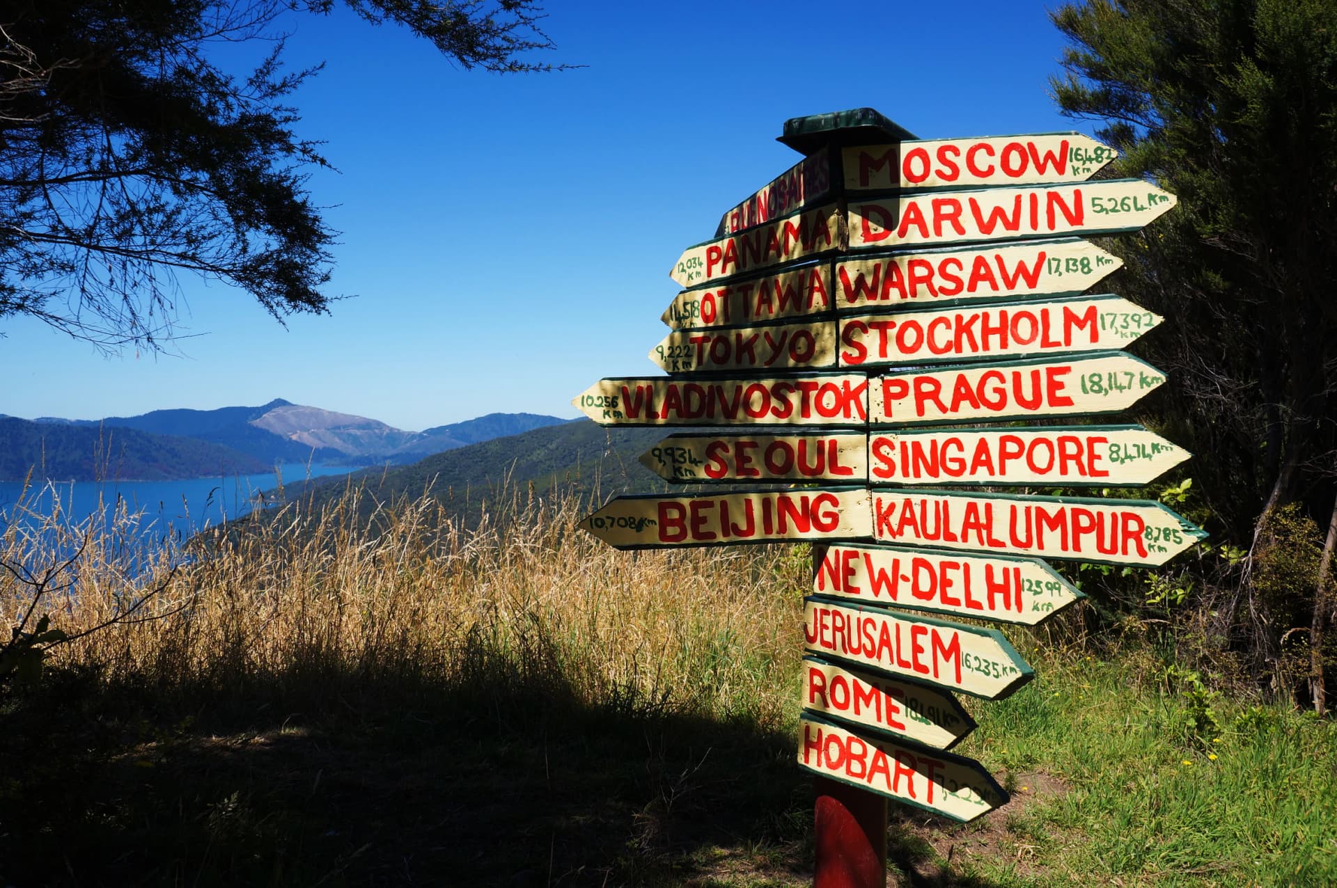 Wooden signpost in Queen Charlotte Track showing distance to international cities around the World, New Zealand